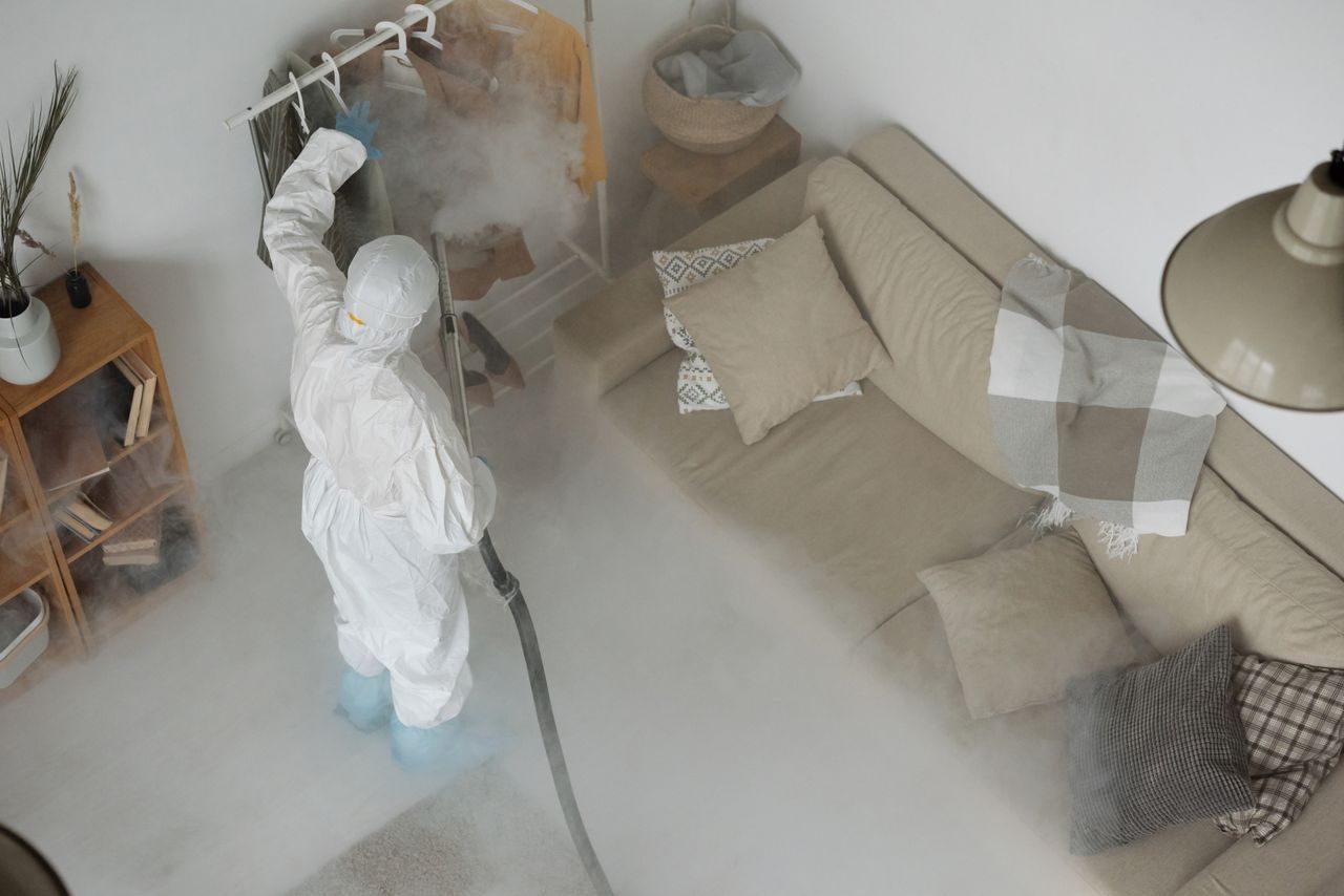 hero illustration Person in protective gear sanitizing home interior for COVID-19 safety.